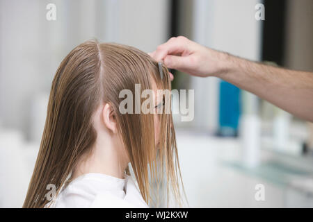 Vista laterale della giovane donna getting haircut al salone di bellezza Foto Stock