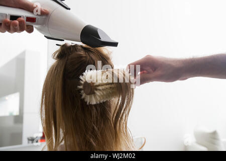 Vista posteriore del giovane donna ottenendo il suo pelo essiccato a salone di bellezza Foto Stock