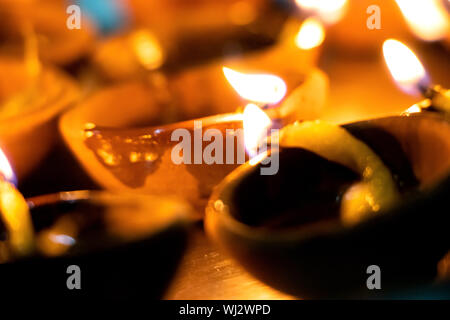 Riprese macro di diyas essendo illuminata da mano o candela per i religiosi indù festa di Diwali. Queste colorate earthern pentole contenere olio e uno stoppino di cotone t Foto Stock