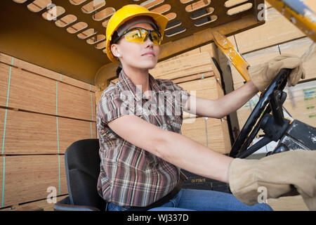 Femmina lavoratore industriale la guida carrello elevatore impilati con doghe in legno in background Foto Stock