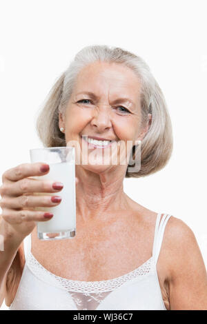 Ritratto di sorridente donna senior con un bicchiere di latte contro uno sfondo bianco Foto Stock