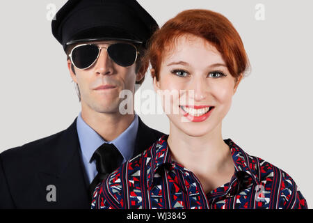 Ritratto di donna felice assistente di volo e pilota contro uno sfondo grigio Foto Stock