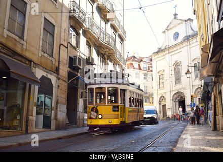 Un tradizionale tram giallo nelle strette vie della città vecchia di Lisbona Portogallo Foto Stock
