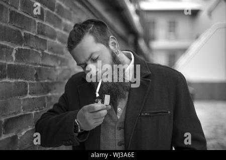 Un uomo con una barba fumi. foto in bianco e nero. Foto Stock