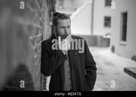 Un uomo con una barba fumi. foto in bianco e nero. Foto Stock