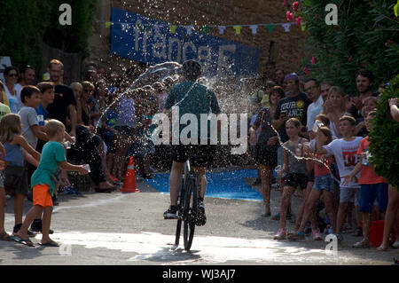 Azione dal ciclo di razza, un breve tratto in salita, nel villaggio di Mianigues, Pla d'lestany, Girona, Spagna. I concorrenti sono cosparsi di fan. Foto Stock