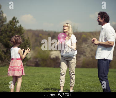 Famiglia lanciando la palla a vicenda nel parco Foto Stock