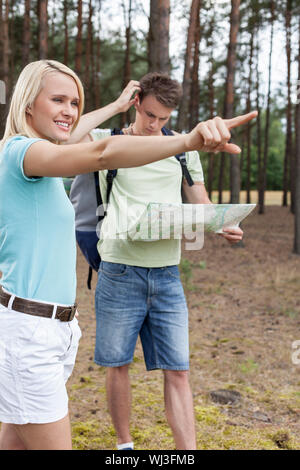 Giovane donna rivolto lontano con confuso uomo azienda mappa nella foresta Foto Stock