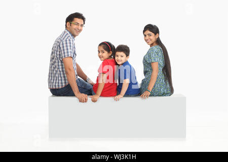 Family sitting on a bench and smiling Stock Photo