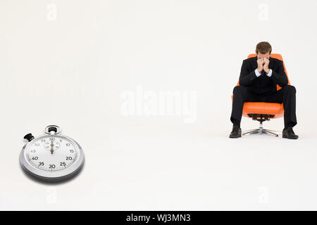 Preoccupato per il businessman seduti su una sedia con il cronometro che rappresenta la perdita di tempo Foto Stock