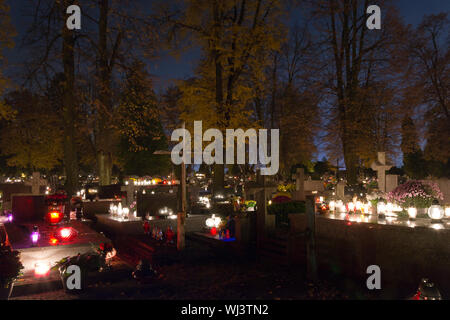 Le candele e i crisantemi a notte nel cimitero Foto Stock