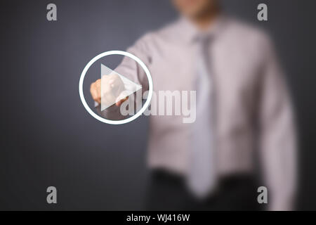 Uomo d'affari che preme il tasto startplay sullo schermo virtuale Foto Stock