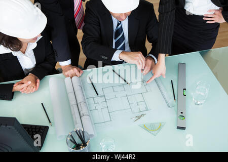 Vista aerea di un gruppo di architetti e ingegneri strutturali a discutere un piano disposto sul tavolo di fronte a loro Foto Stock