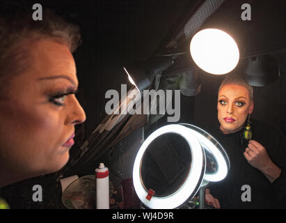 Gravi drag queen nella parte anteriore dello specchio con lampada Foto Stock