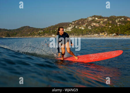 Surfista femmina a cavallo delle onde oceaniche, Sayulita, Nayarit, Messico Foto Stock