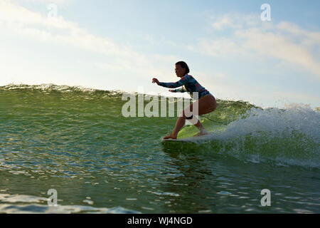 Surfista femmina a cavallo delle onde oceaniche Foto Stock