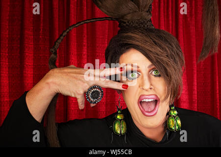 Ridendo Caucasian drag queen in teatro con la mano vicino al viso Foto Stock