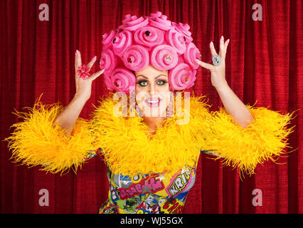 Uomo felice nel vestire e gommapiuma rosa parrucca eseguendo Foto Stock