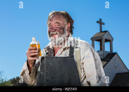 Il vecchio West ubriacone beve una bottiglia di alcool Foto Stock