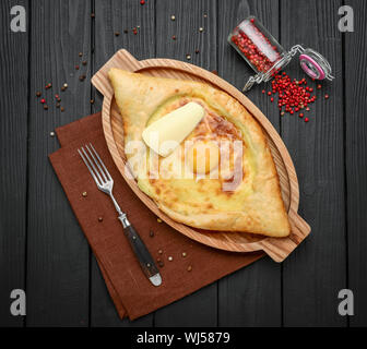 Mano miscelando gli ingredienti di adjarian khachapuri con forcella in ristorante. Aprire il grafico a torta di pane con formaggio e tuorlo d'uovo. Squisita cucina georgiana. Slow motion. Foto Stock