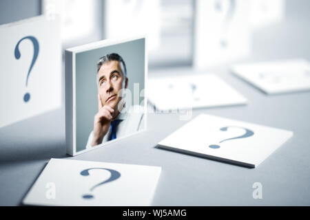 Ritratto di un imprenditore confuso circondato da un punto interrogativo Foto Stock