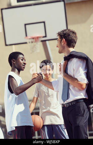 Multi-Ethnic giocatori di basket stringono le mani dopo la partita Foto Stock