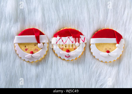 Biscotti di Natale con santa faccia sul pelo bianco sfondo in una fila con spazio di copia Foto Stock