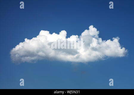 Una nuvola bianca che vola attraverso il cielo blu Foto Stock