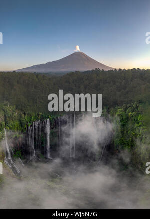 Antenna fuco immagine di Tumpak Sewu cascata con il Monte Semeru eruzione vulcanica in background in Java Orientale, Indonesia Foto Stock