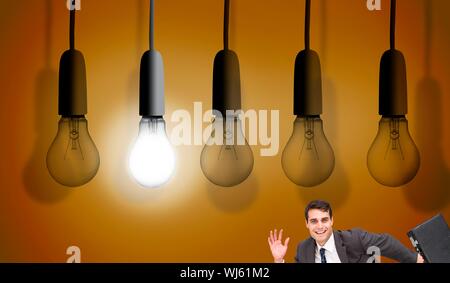Immagine composita di happy businessman in possesso di una valigetta e in esecuzione sotto l'enorme lampadine su sfondo arancione Foto Stock