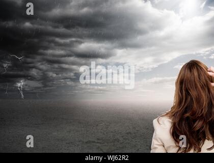 Immagine composita della classe imprenditrice di graffiare la sua testa sotto il cielo in tempesta Foto Stock