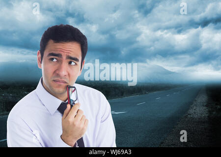 Immagine composita di pensare imprenditore tenendo gli occhiali Foto Stock