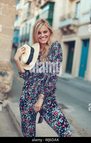 Felice alla moda giovane donna bionda che pongono al Mediterranean street in posa Foto Stock