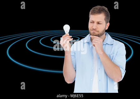 Immagine composita del modello scettico su sfondo bianco in possesso di una lampadina Foto Stock