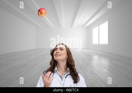 Immagine composita di felice brunette medico gettando apple Foto Stock