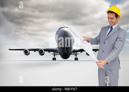 Immagine composita di sorridere architetto con elmetto guardando i piani Foto Stock