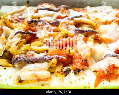 Cucina francese - zucchini cotto con fette di peperone e pomodoro con topping da cheece Parmigiano, aglio e acciughe con condimento di olio di oliva Foto Stock