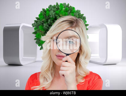 Immagine composita del biondo donna guardando attraverso una lente di ingrandimento Foto Stock