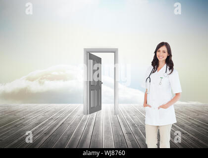 Immagine composita di fiduciosa medico donna in piedi di fronte alla finestra mentre sorridente Foto Stock