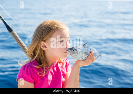 Blonde kid ragazza la pesca di tonno piccoli tonni kissing fish per il rilascio a causa ridotte dimensioni Foto Stock