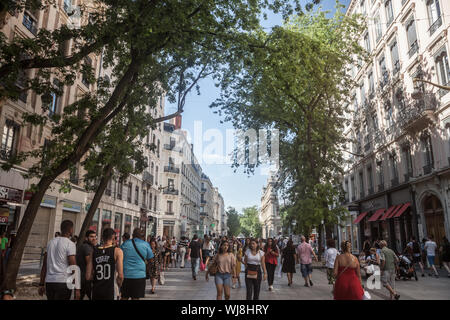 Lione, Francia - 13 luglio 2019: folla di pedoni a piedi su Rue de la Republique Street a Lione, in Francia, di fronte a edifici in stile Haussmann e comm Foto Stock