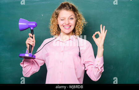 Giorno della conoscenza. Concetto di illuminismo. Creatività e ispirazione. Indicatore di direzione sul. Luce adeguata classe. Luce fino processo di studio. Insight e l'idea. Insegnante tenere la lampada da tavolo lavagna sfondo. Foto Stock