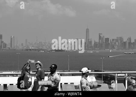 Passeggeri prendono un selfie davanti lo skyline di New York, mentre l'equipaggio servire bevande a bordo l'Inno dei mari Royal Caribbean Cruise Ship. Foto Stock