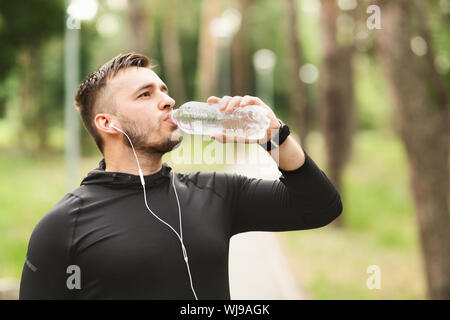 Athletic uomo acqua potabile dopo allenamento nel parco Foto Stock