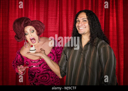 Sorridente uomo latino con fame drag queen e tortina Foto Stock