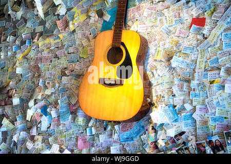 Fenghuang, Cina. Settembre 13, 2015. Una chitarra acustica appeso a una parete con foglietti adesivi e i biglietti del treno in un coffee shop all'interno di Fenghuang ancie Foto Stock