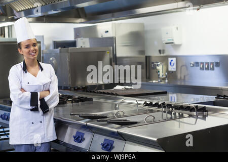 Giovani chef sorridente in piedi accanto alla superficie di lavoro in cucina professionale Foto Stock
