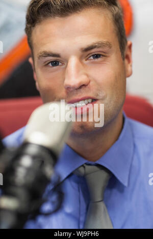 Ben vestito sorridente host radio moderare in studio presso il college Foto Stock