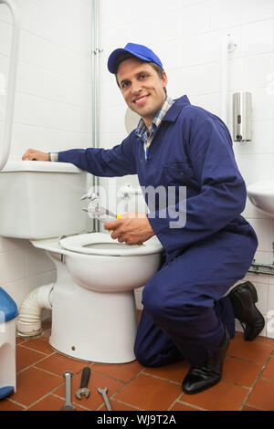 Buona ricerca plumber riparazione di toilette in bagno pubblico Foto Stock