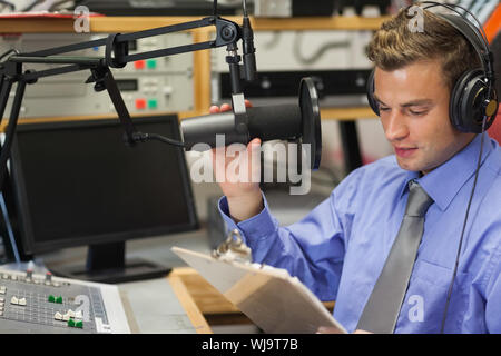 Ben vestito focalizzato host radio la moderazione di seduta in studio presso il college Foto Stock